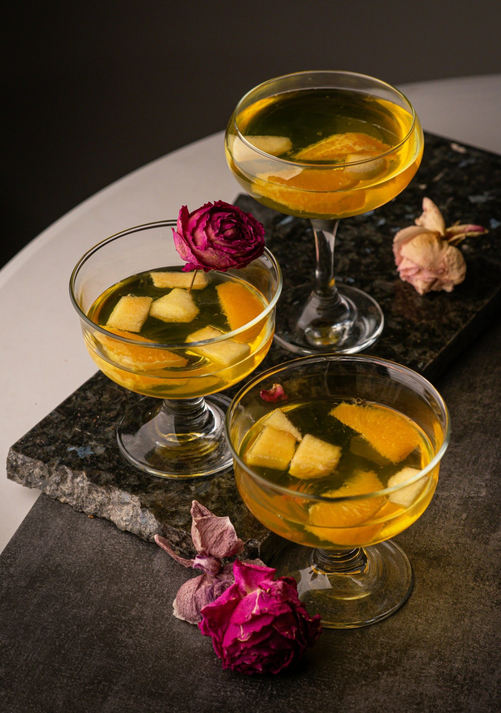Three glasses filled with drinks sitting on top of a table
